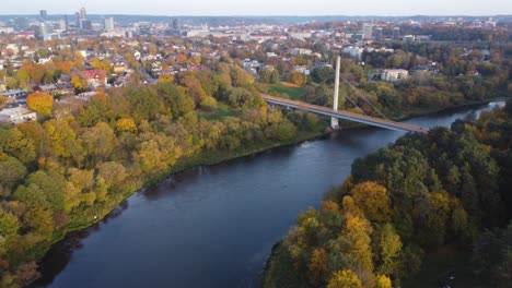 Toma-Aérea-En-órbita-De-Un-Barrio-Suburbano-Žvėrynas-En-Vilnius,-Lituania-Con-Un-Río-Serpenteando-A-Través-Del-Follaje-Otoñal