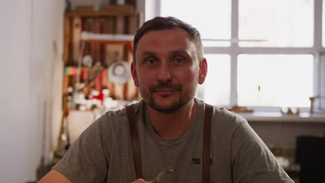 Smiling-worker-with-smoking-pipe-in-home-workshop-closeup