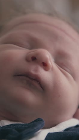 careful young mummy holds adorable little baby wearing elegant festive tuxedo in light room extreme close view