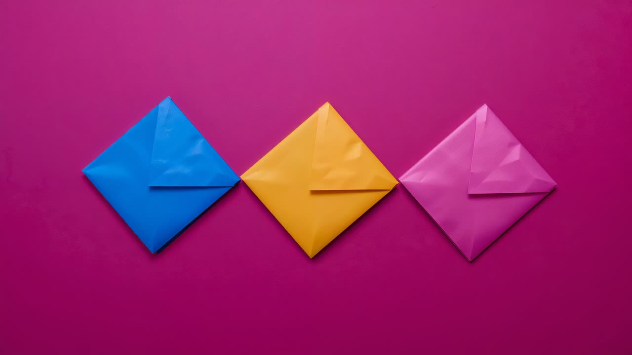 After stillness, hand entering magenta desk, pulling pink envelope aside then realigning trio flush