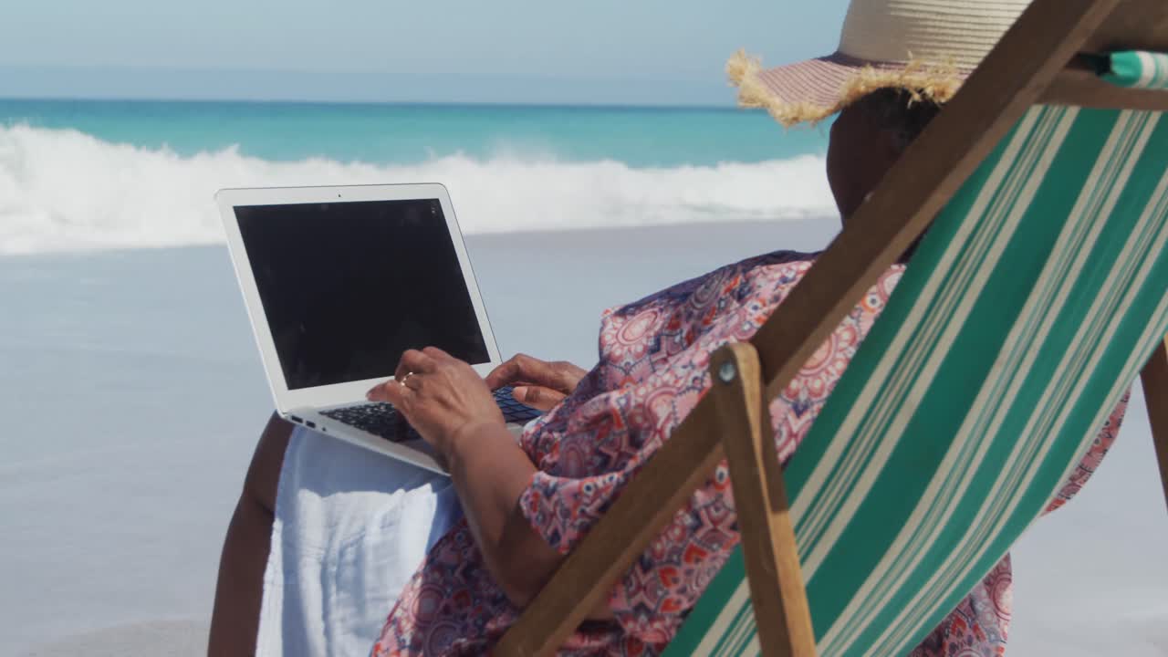 mujer mayor usando una computadora portátil en la playa