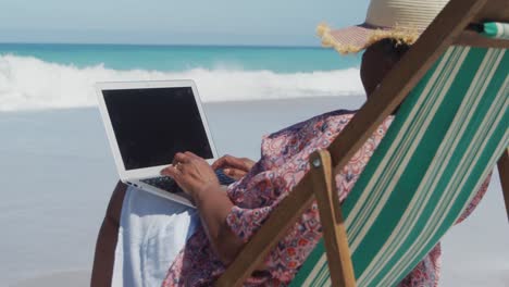 senior woman using laptop at the beach