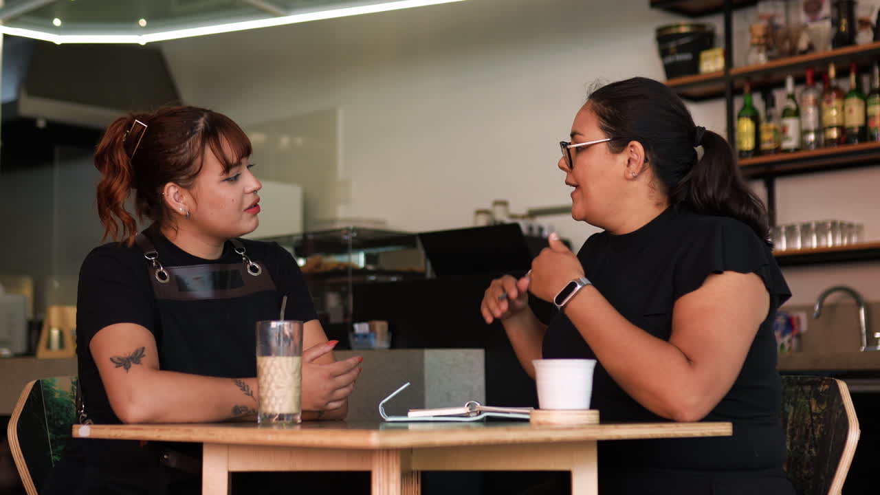 dos mujeres hablando y sentadas en una mesa