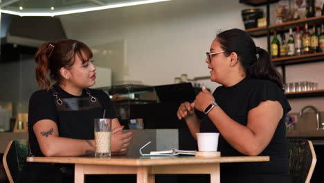 Two-women-talking-and-sitting-on-a-table