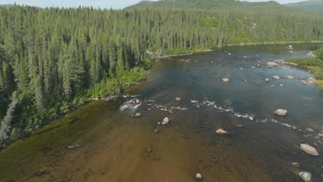 wide angle drone shot looking down on an air boat travelling through the rivers of newfoundland and labrador, canada