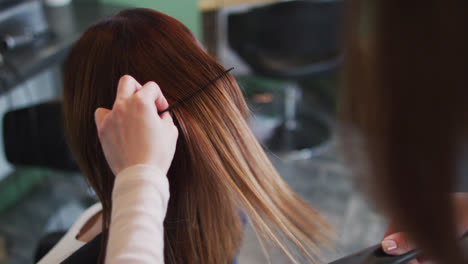 peluquera que endereza el cabello de una cliente en un salón de peluquería
