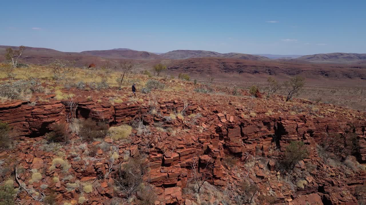 excursionista caminando por el borde de una montaña rocosa con el paisaje en el fondo, desierto de australia occidental