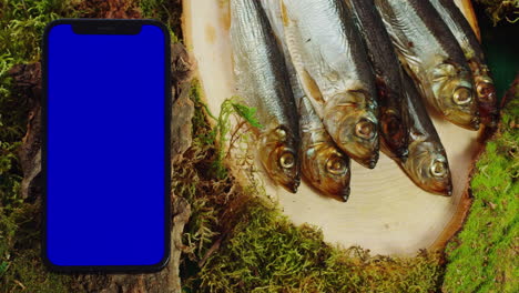 smoked fish on a wooden board with a smartphone