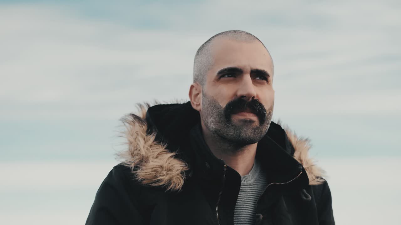 un hombre guapo se para en una montaña, mirando el impresionante paisaje de nubes en el horizonte