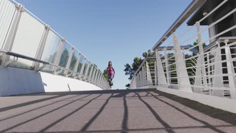 African-american-woman-wearing-face-mask-running-on-the-city-bridge