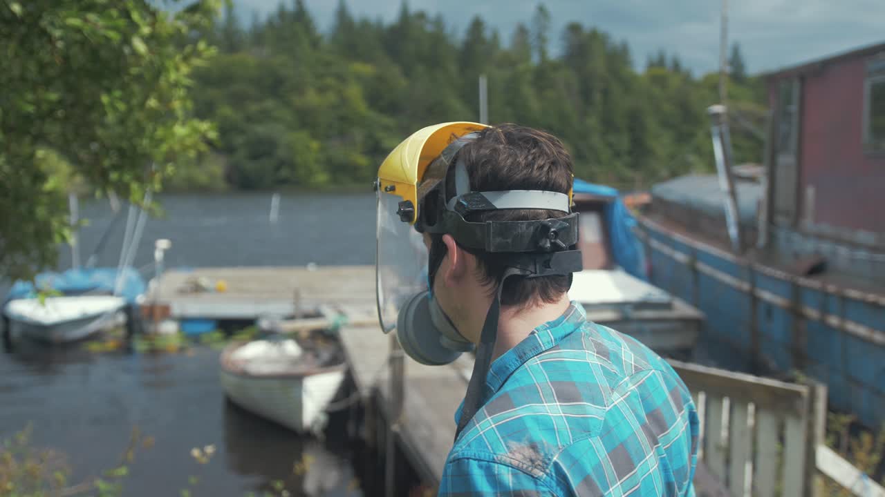 un joven baja la visera sobre su cara trabajando en un astillero