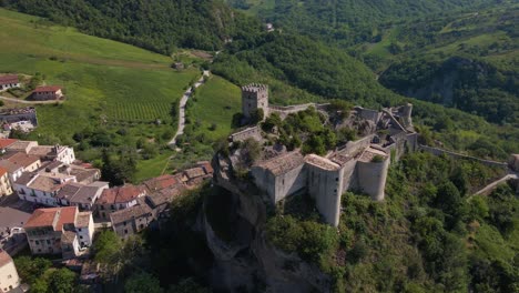 drone shot orbiting the medieval castle on a cliff called roccascalegna in the region of abruzzo in italy revealing the panoramic views surrounding the castle with mountains and vineyards