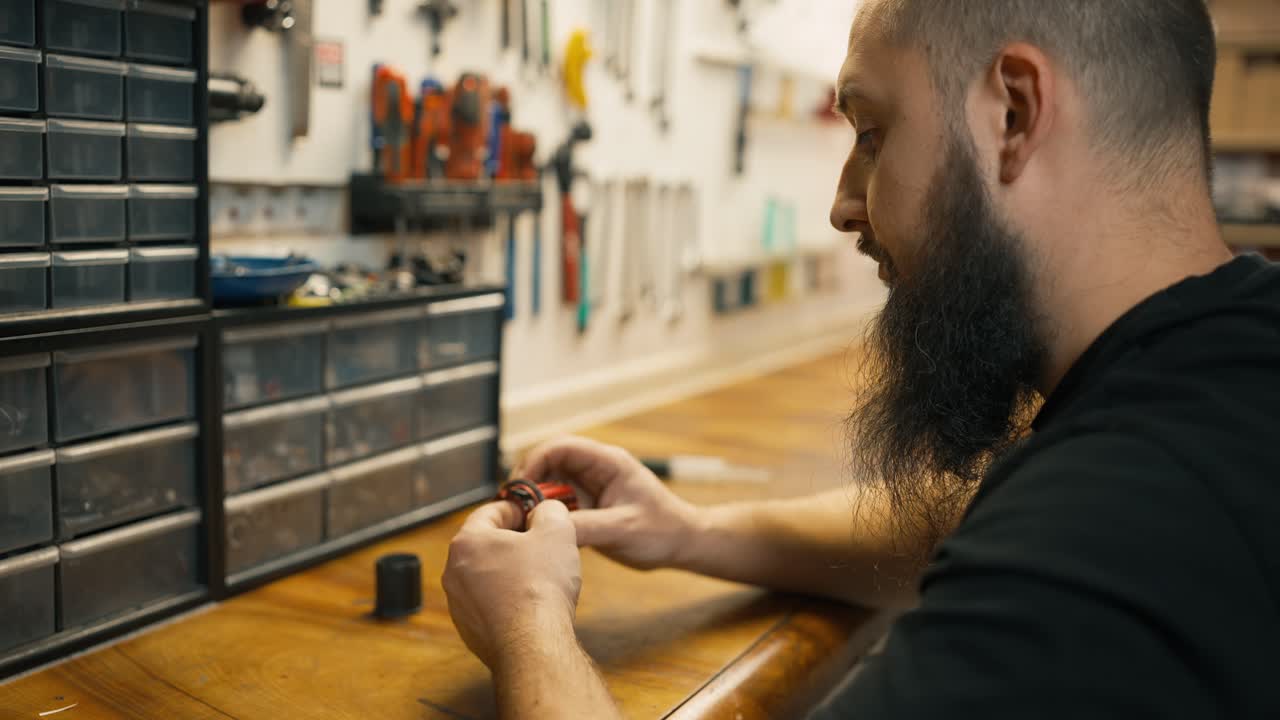 어떤 자전거 부품, 느린 동작과 함께 테이블에 앉아 젊은 백인 수리사