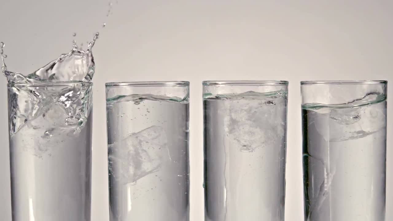 Isbitar faller ner i ett glas vatten