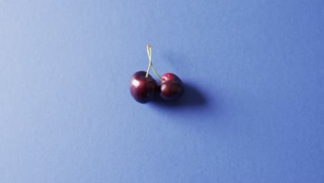 Video-of-close-up-of-cherries-with-copy-space-over-blue-background