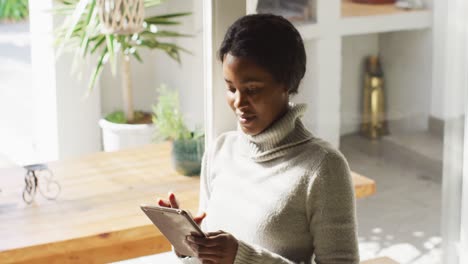 Video-of-happy-african-american-woman-using-tablet-at-home