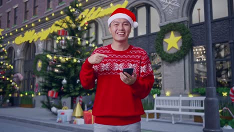 man in christmas sweater using smartphone