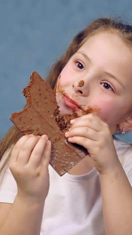 young girl eating chocolate bar. happy cutegirl isolated over background eating chocolate