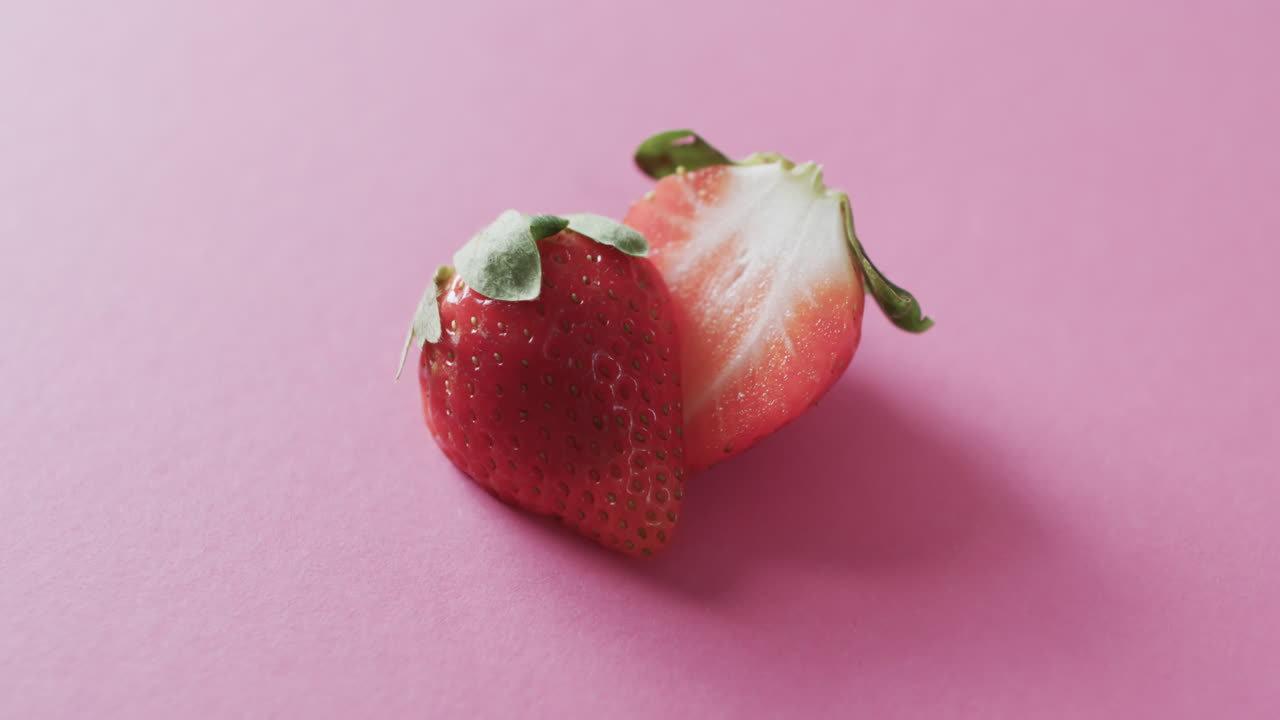 video de fresa cortada por la mitad con espacio de copia sobre fondo rosa