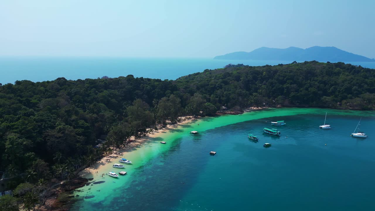 Koh Wai Bay Beach with boats anchored in turquoise waters. Dramatic aerial view flight wide orbit overview drone