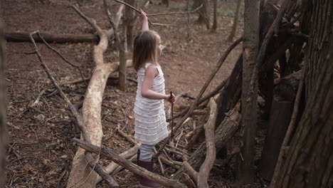 Niña-Pequeña-Construyendo-Un-Fuerte-De-Palo-En-Un-Bosque,-Cámara-Lenta