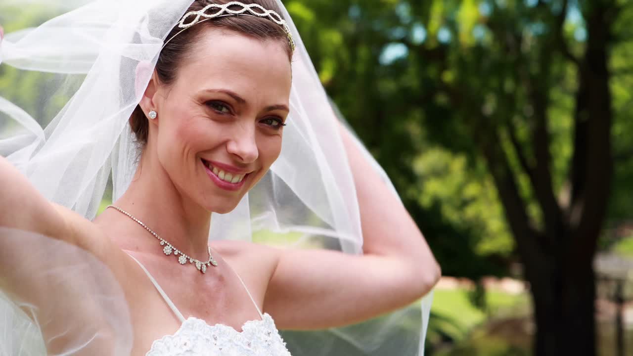 Mooie bruid lachend naar de camera en haar sluier optillend