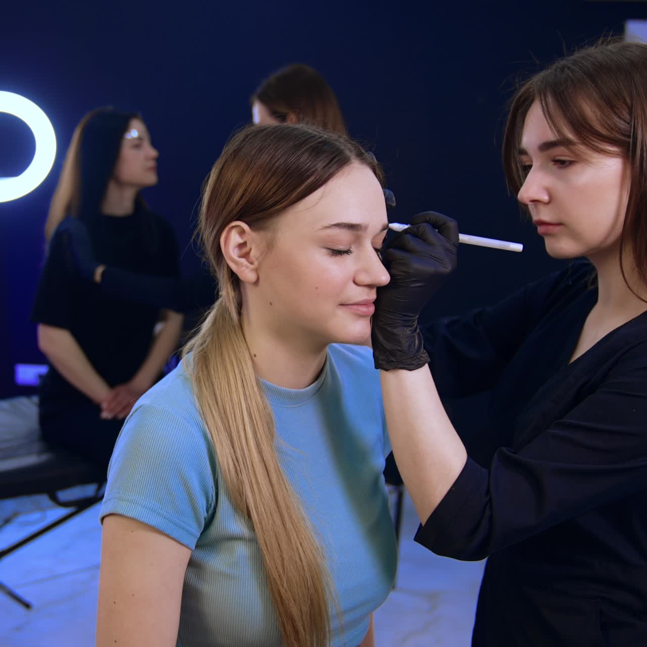 Female clients having eyebrow make up in the beauty salon. Cosmetologist marks the lines with white pencil