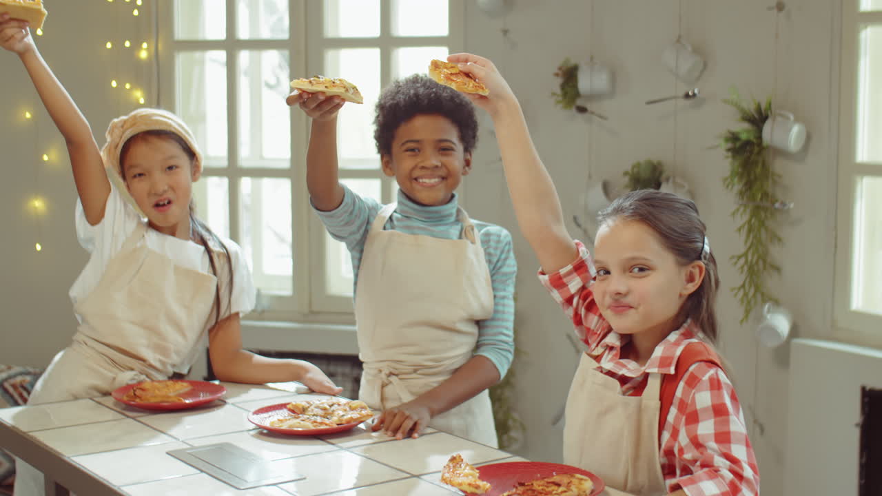 Ritratto di bambini multietnici felici con la pizza a un corso di cucina