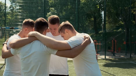 young street football players standing in a huddle on the pitch before game