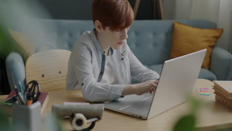 teenage boy working on laptop at home