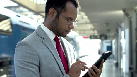 businessman with digital tablet at train station