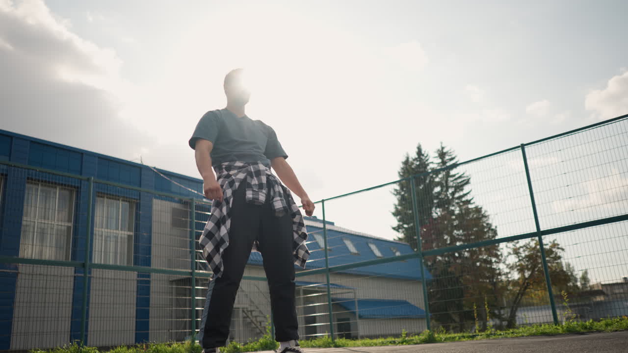 배경에는 초록색, 건물, 스포츠 장비가 있는 야외 코트에서 주먹을 고 승리로 포즈를 취하고 있는 배경에 배경이 있는 선수.