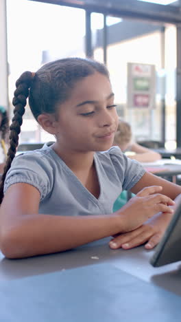 vertical video: in school, young girl with a braid focusing on a tablet