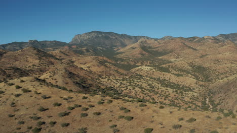 Aerial-moving-along-ridge-with-arid-desert-mountains-in-background,-4K