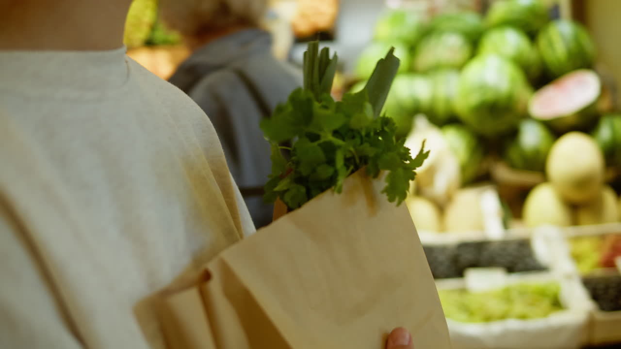 Person Holding Paper Bag with Fresh Herbs at Market