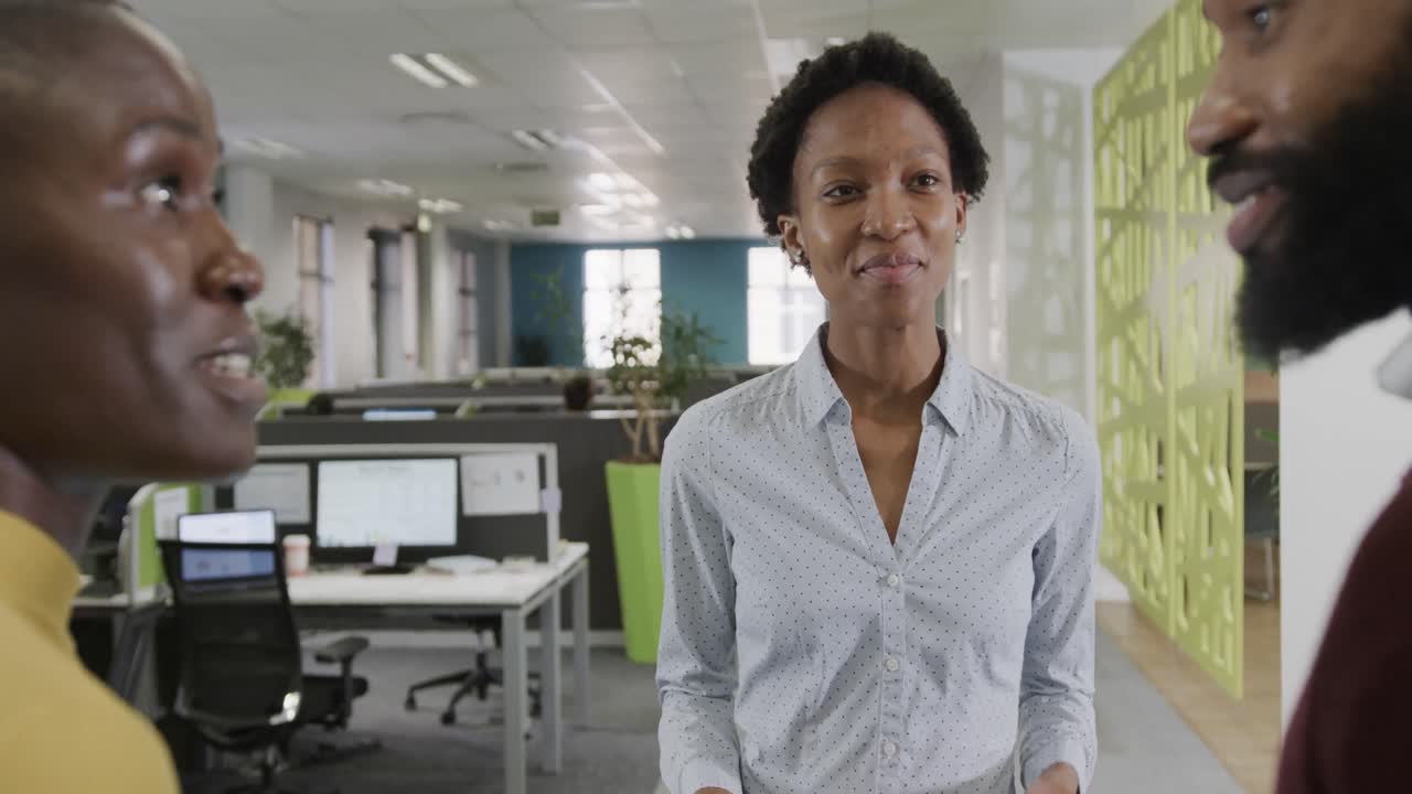 felices colegas de negocios afroamericanos, hombres y mujeres, discutiendo en la oficina, cámara lenta.