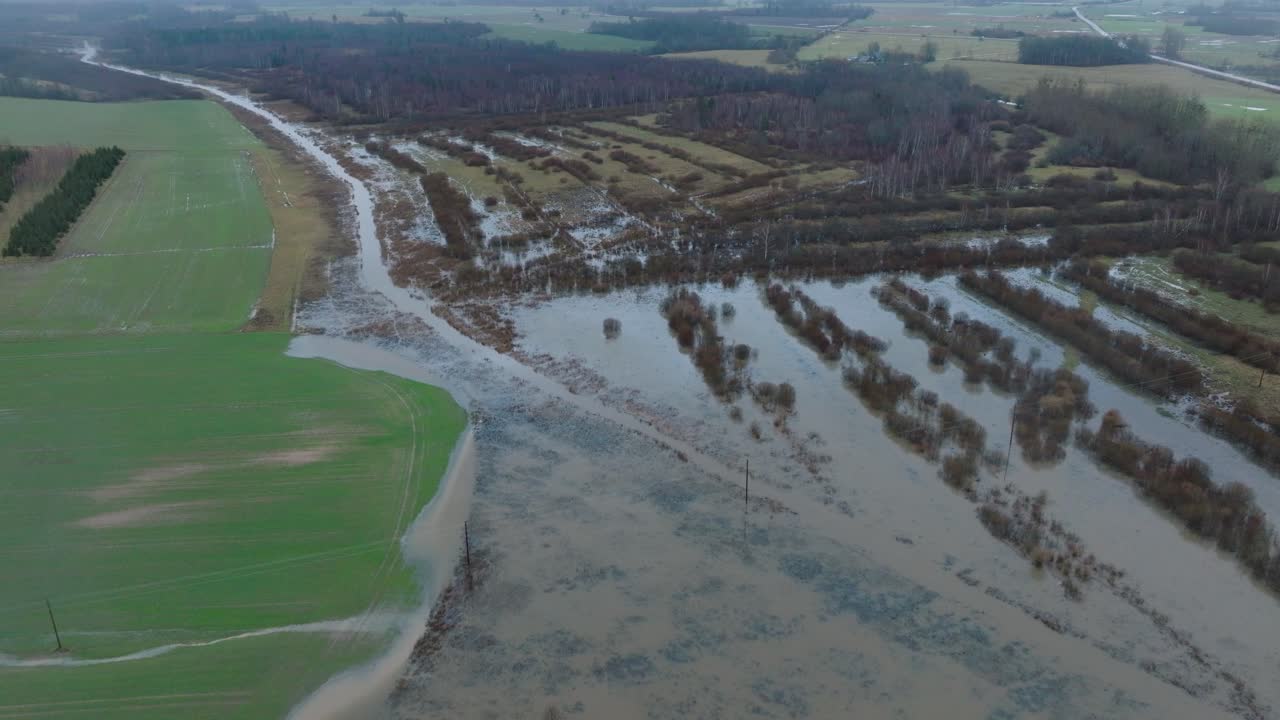 Aerial establishing view of high water in springtime, Alande river flood, brown and muddy water, agricultural fields under the water, overcast day, wide birdseye drone shot moving forward