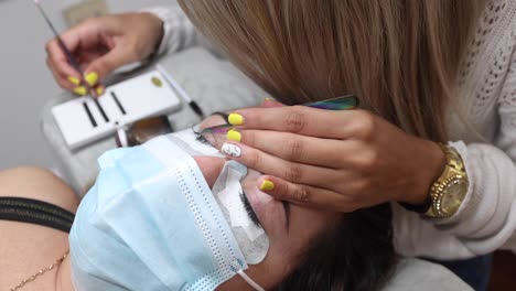 esteticista de cultivos aplicando pestañas en la cara de la mujer