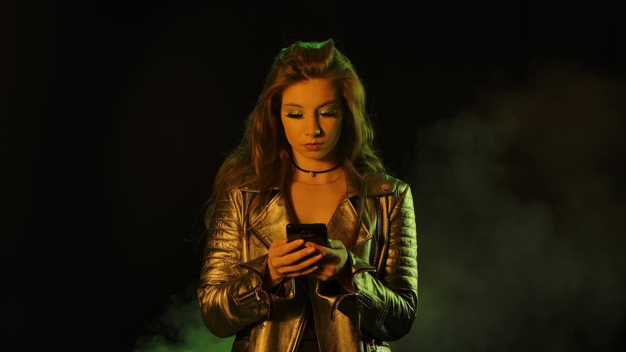 Ritratto di una giovane donna carina e turbata che sta messaggiando, poi mostra indignata lo smartphone con uno schermo verde chroma key alla telecamera. Primo piano. Movimento lento.
