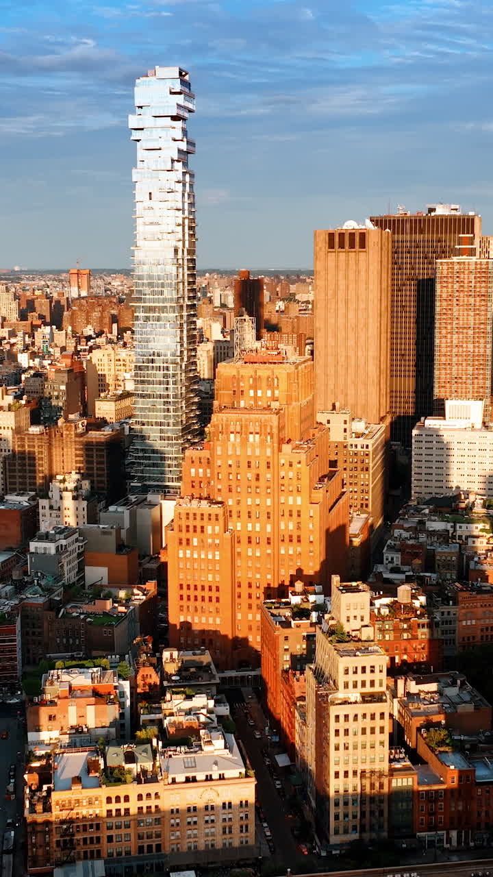 Bright sun lighting the diverse dense architecture of New York. Golden hour footage of cityscape from drone. Vertical video