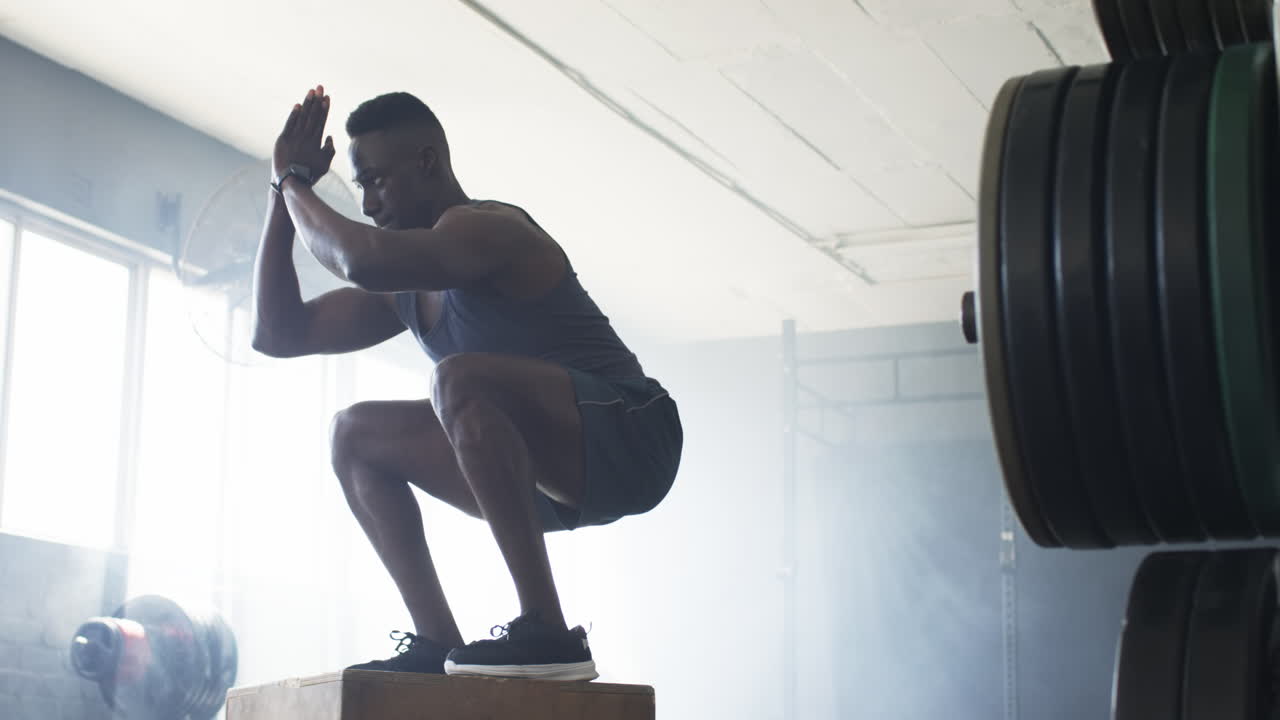 Jumping onto box, man exercising in gym, focusing on fitness training