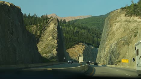 Driving-down-a-4-lane-freeway-in-the-middle-of-the-Rocky-Mountains,-Alberta,-Canada