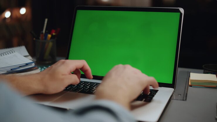 Freiberuflerhände tippen auf Greenscreen-Laptop in dunklem Raum, Nahaufnahme. Mann tippt.