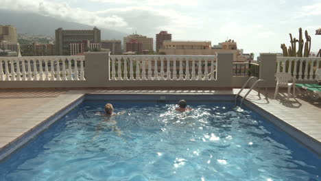 couple relaxing by hotel rooftop swimming pool