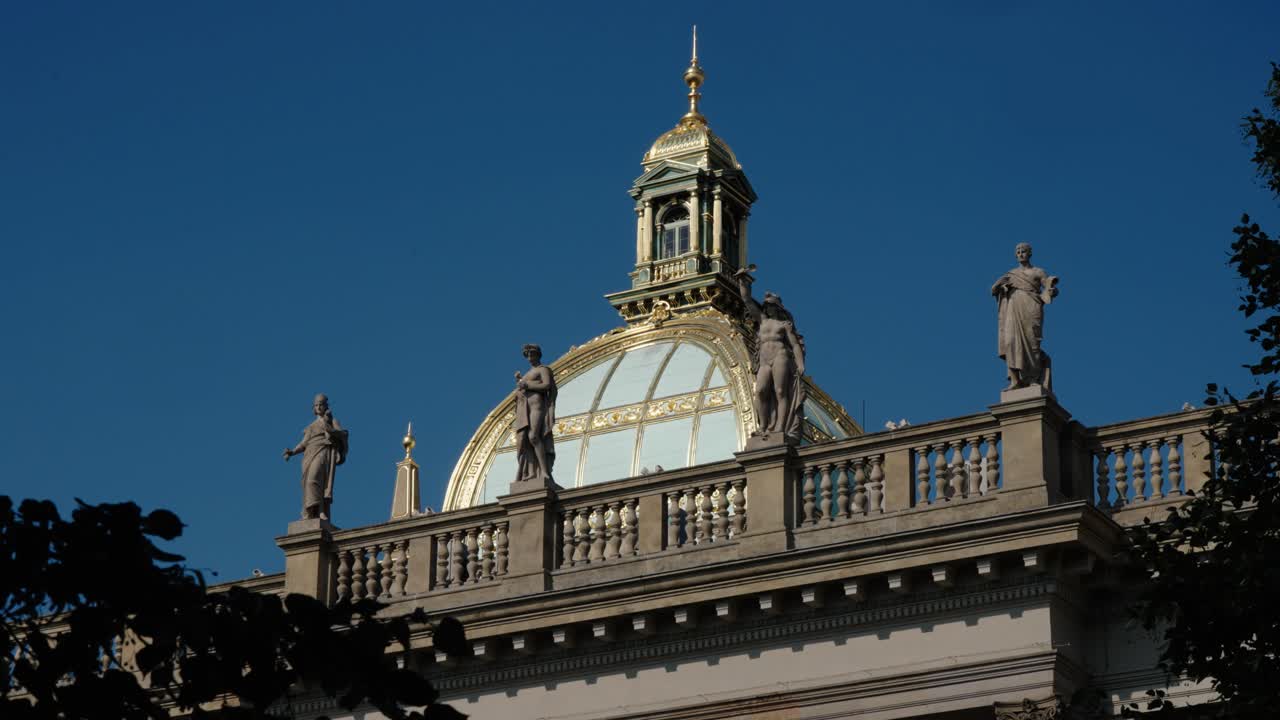 Golden dome and statues of Prague’s National Museum framed by clear blue sky