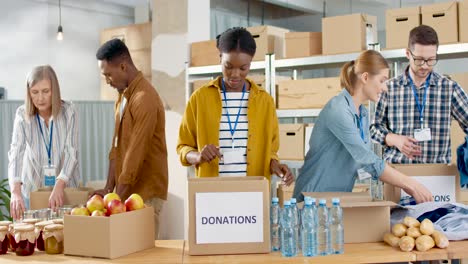 multiethnic group of volunteers packing boxes with food and clothes in charity warehouse