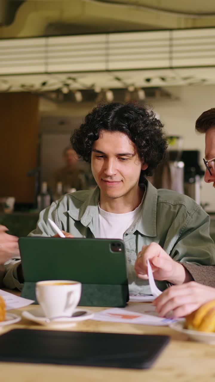 Young Man Using Digital Tablet During Business Meeting in Cafe