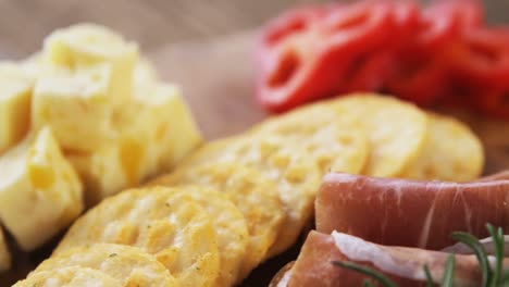 cheese, crispy biscuits and meat on wooden board