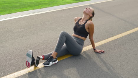 woman with prosthetic leg resting after workout. girl relaxing after jogging