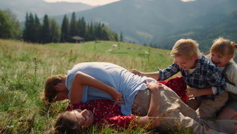 Familia-Tumbada-En-La-Hierba-Verde-Apilada-Una-Encima-De-La-Otra-Día-Soleado-Padres-Jugando-Con-Niños